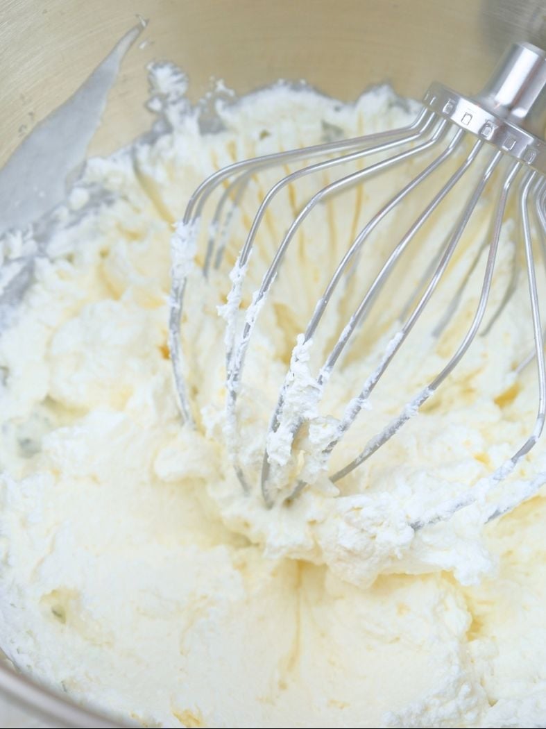 Homemade vanilla whipped cream in a mixing bowl with wire whisk