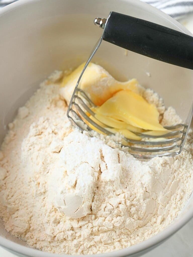 Flour, salt, and butter in a mixing bowl, shown with pasty cutter.