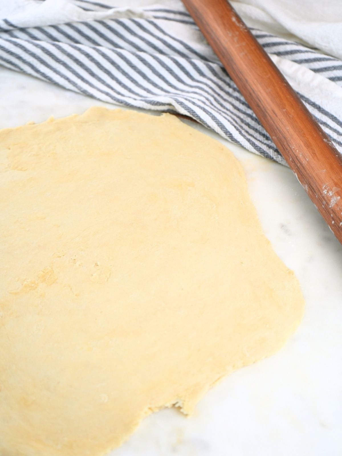Dough rolled out on a counter and a rolling pin.