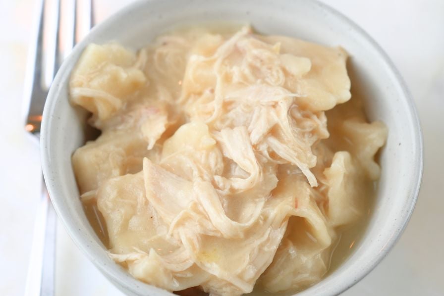 A small bowl of chicken and pastry with a fork next to It
