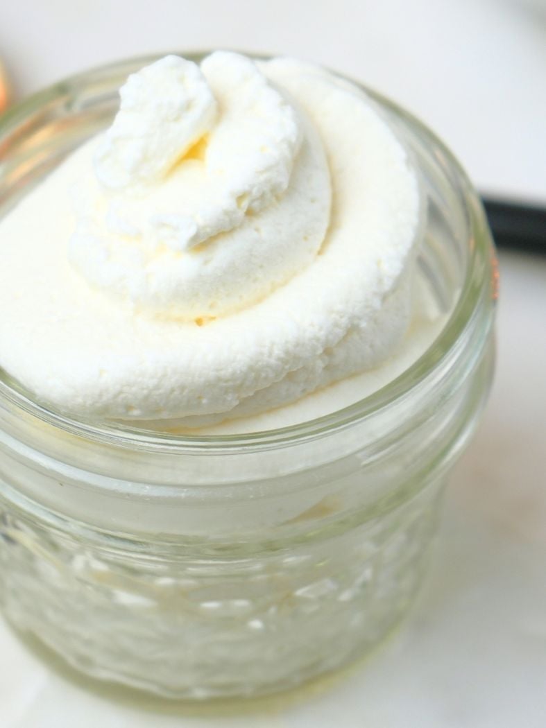 Homemade whipped cream with vanilla in a small glass jar
