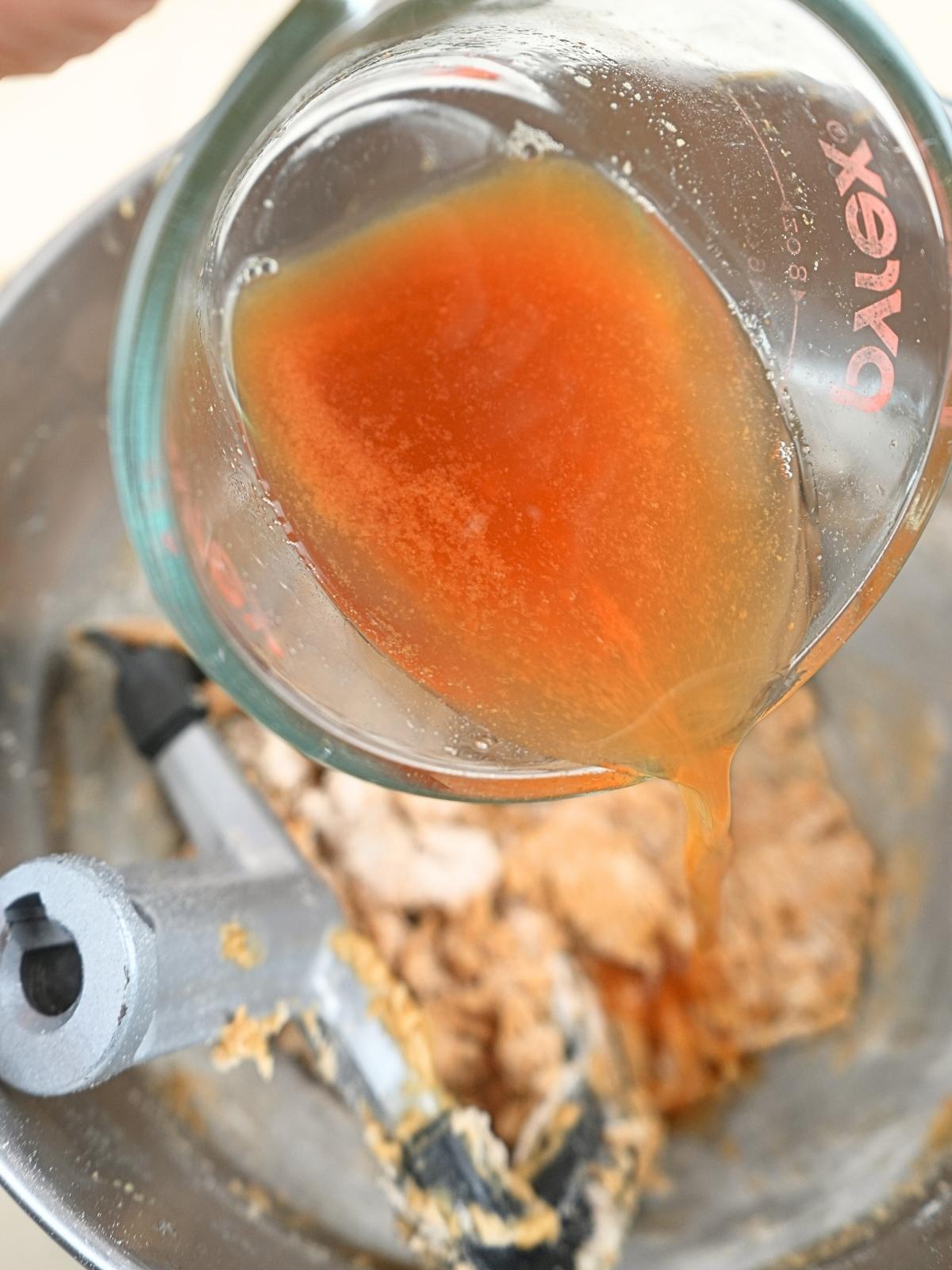 Apple cider being poured in a mixing bowl.
