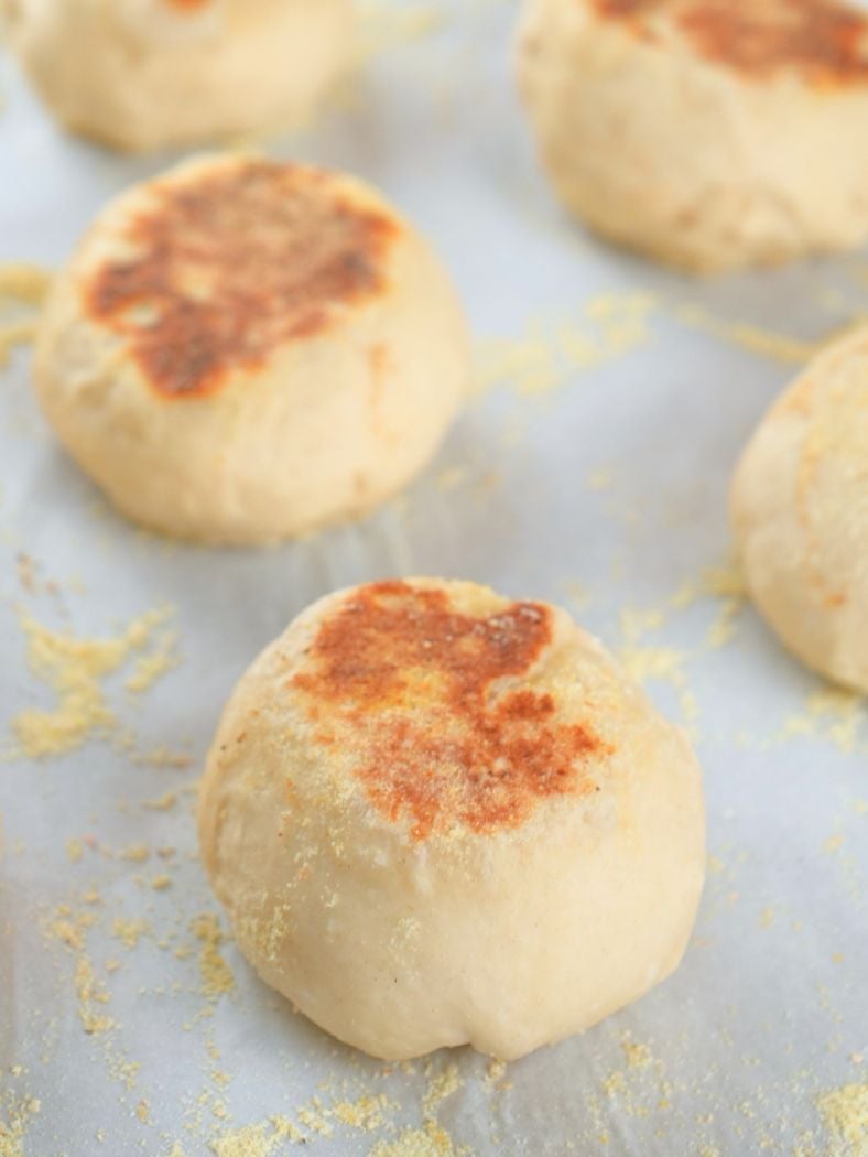 Browned sourdough English muffins on a baking sheet