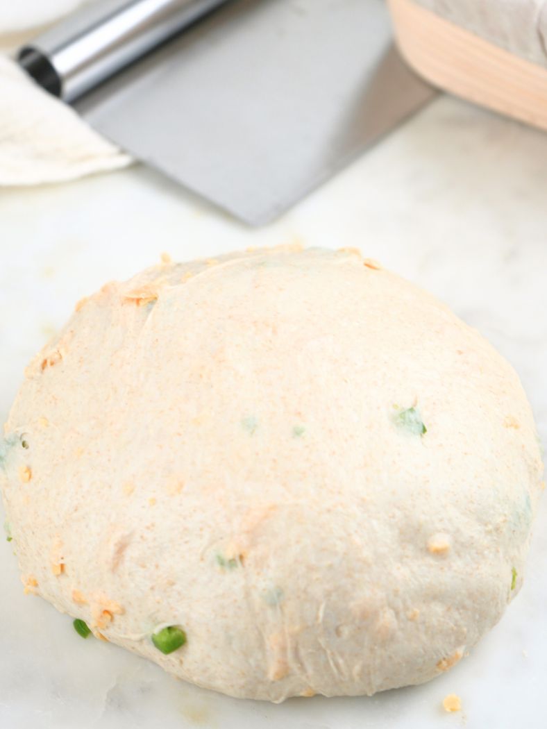 Shaped dough on a counter, shown with a bench scraper