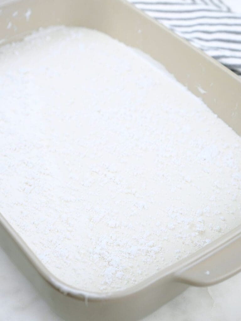 Homemade marshmallow mixture in a baking dish, covered in powdered sugar