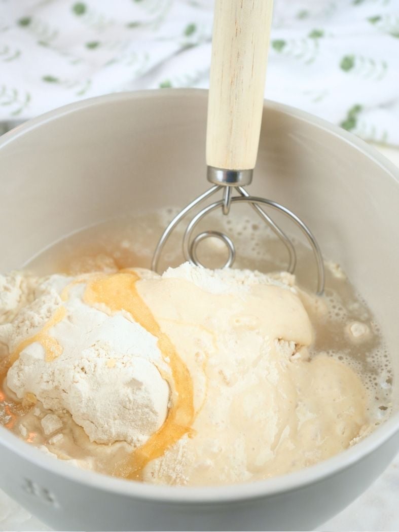 Sourdough English muffin ingredients in a mixing bowl, shown with a Danish dough whisk