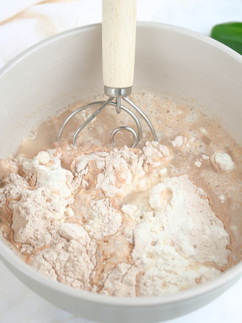 Flour and water in a mixing bowl, shown with a Danish dough whisk