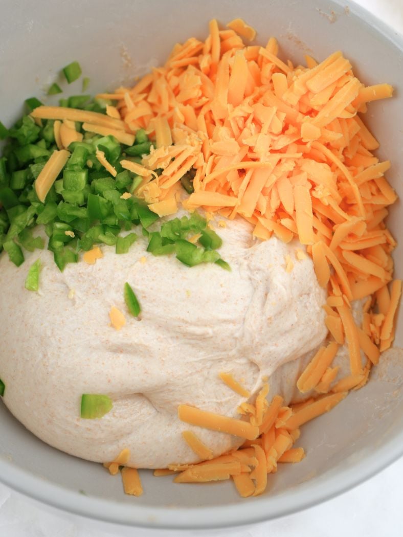 Jalapeños and cheddar cheese on top of bread dough