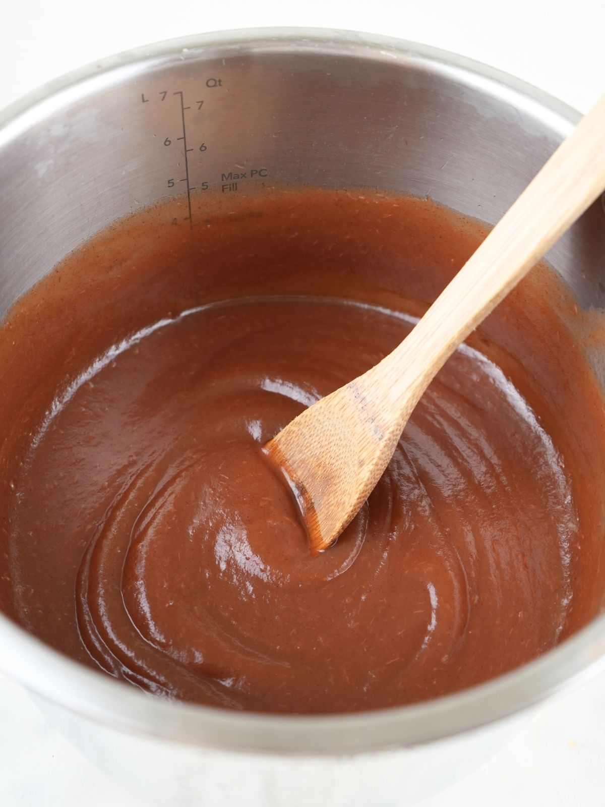 Finished apple butter in an Instant Pot, shown with a wood spoon.