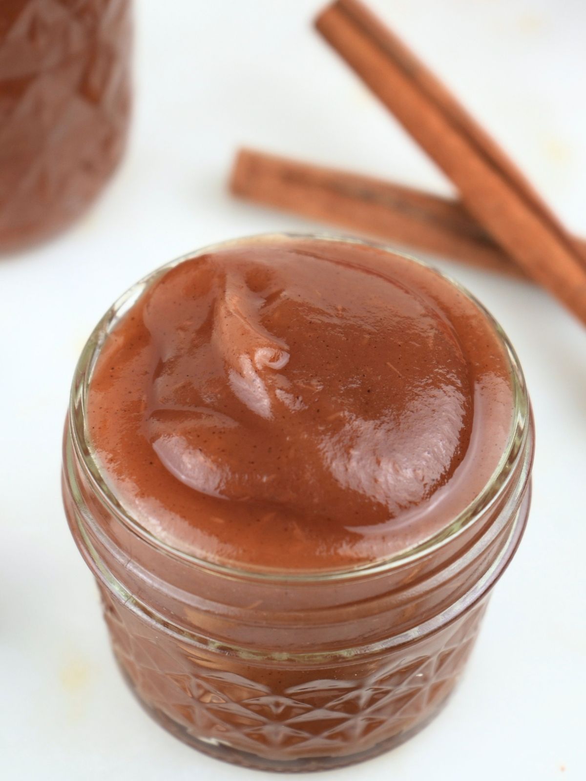 A small jar of Instant Pot apple butter with cinnamon sticks.