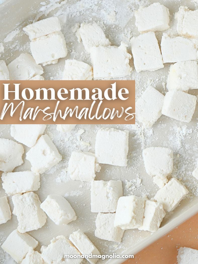 Marshmallows made without corn syrup in a dish, tossed in powdered sugar. Text overlay say, "Homemade Marshmallows"