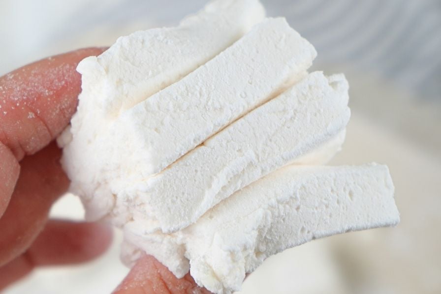 A hand holding sliced homemade marshmallows