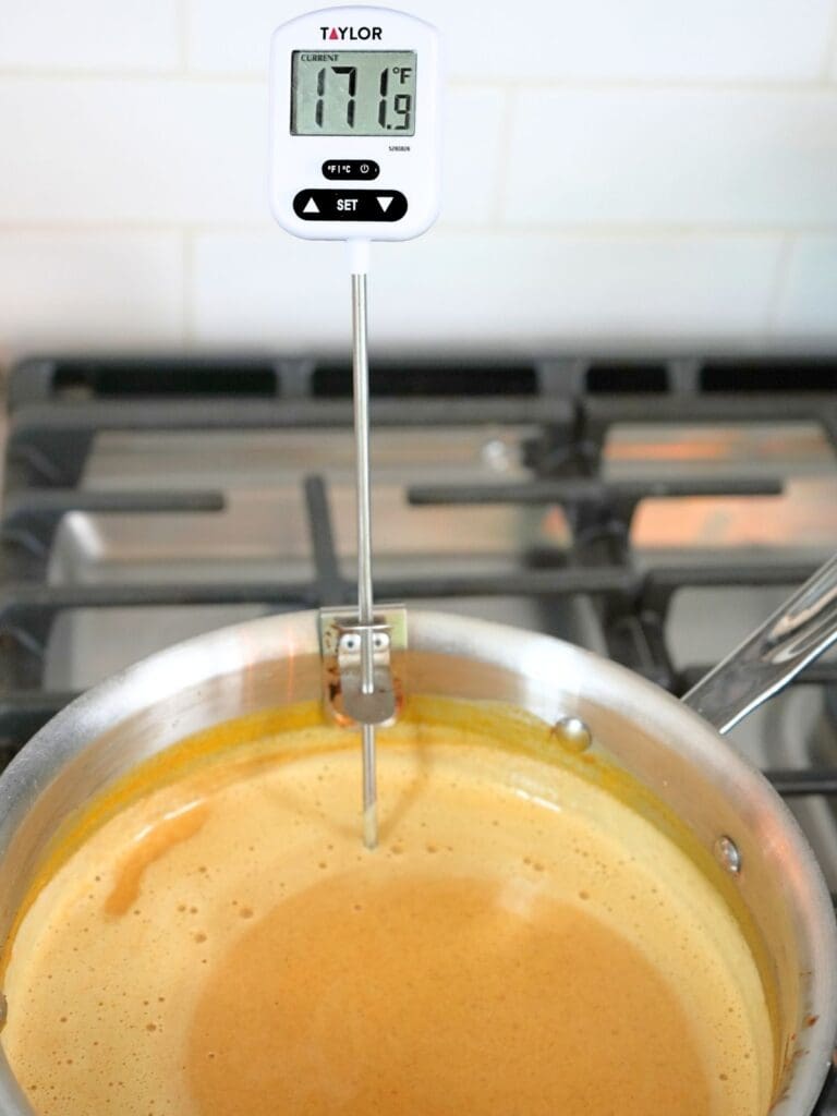 Pumpkin ice cream custard on the stove with a thermometer reading 171 degrees.
