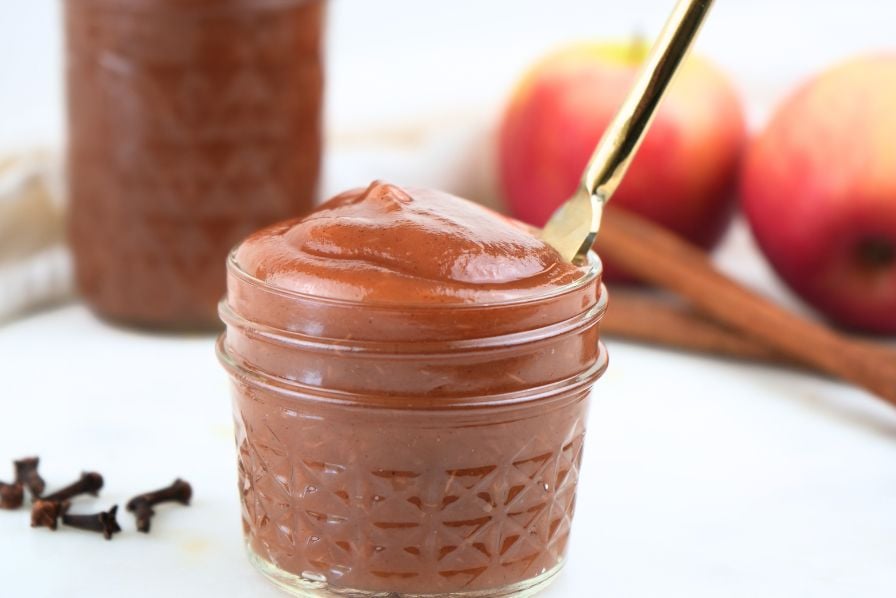 A small jar of Instant Pot apple butter with a gold knife it in