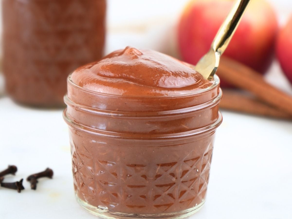 A small jar of Instant Pot apple butter with a butter knife.