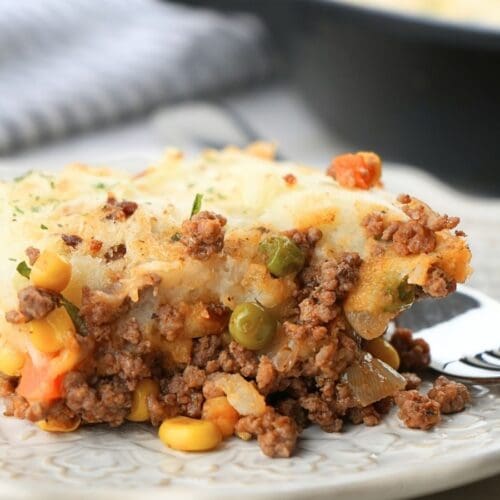 A scoop of shepherd's pie with corn on a plate with a fork.