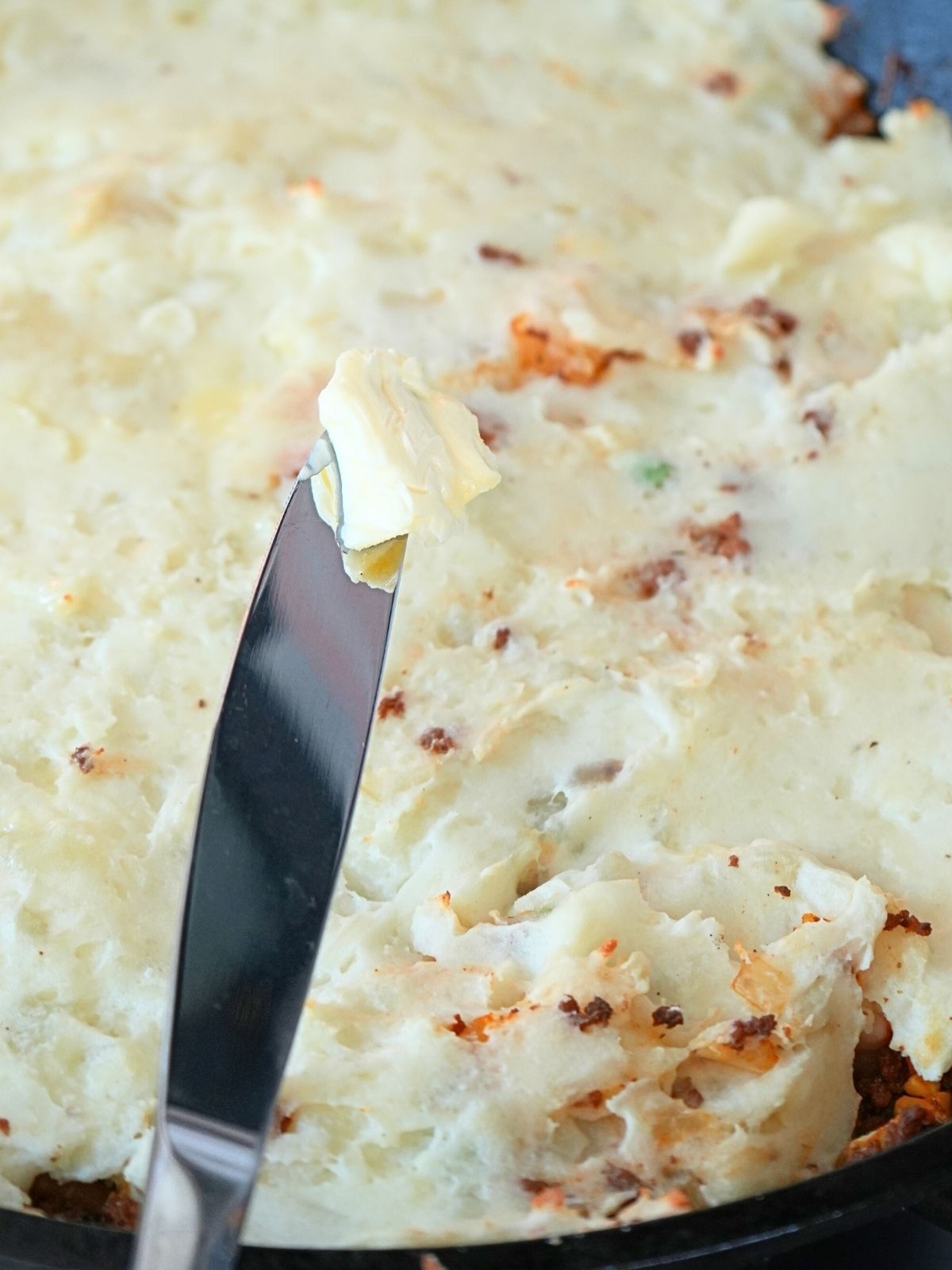 A knife with butter on it.