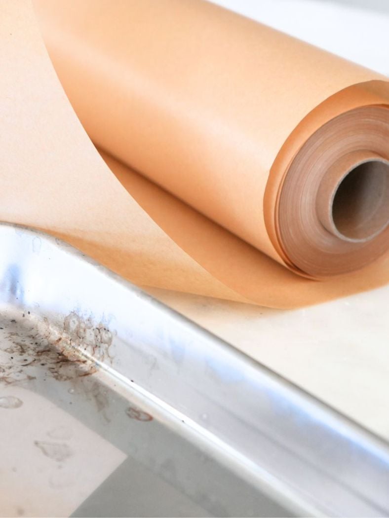 A roll of parchment paper and a baking sheet in the foreground