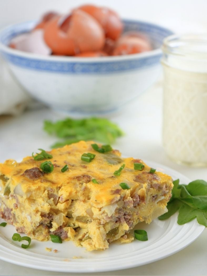 A slice of slow cooker breakfast casserole on a small dish, garnished with greens
