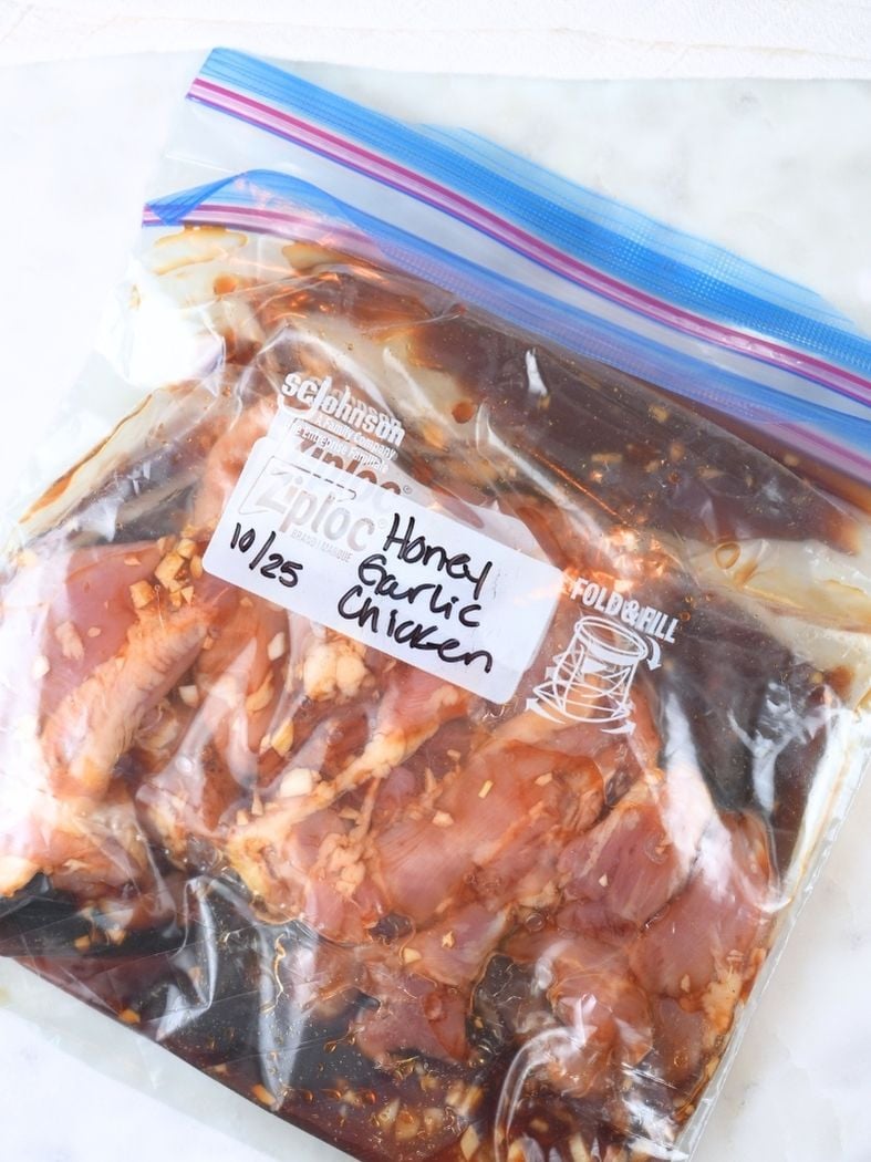 Honey garlic chicken freezer meal laying flat on a counter in a labeled freezer bag