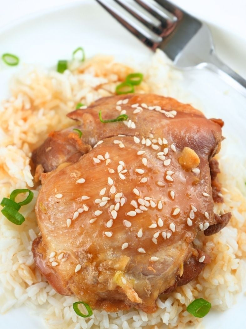 Honey garlic chicken on a bed of rice and garnished with sesame seeds and green onions