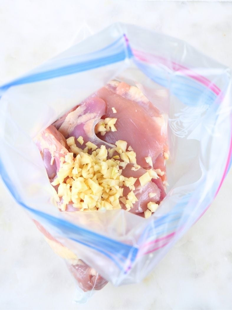 Minced garlic place on chicken thighs inside of a freezer bag