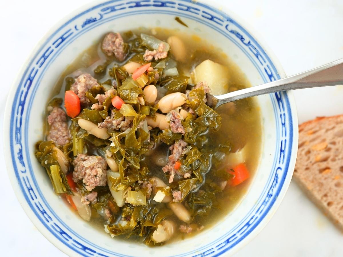 A bowl of one-pot sausage, kale, and white bean soup.