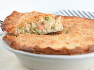 A slice of sourdough chicken pot pie on a pie server being lifted from a pie dish.