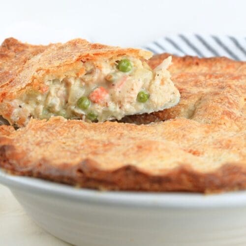 A slice of sourdough chicken pot pie on a pie server being lifted from a pie dish.