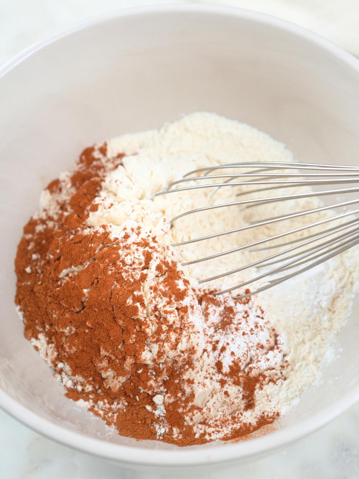 Dry ingredients in a mixing bowl, shown with a wire whisk.
