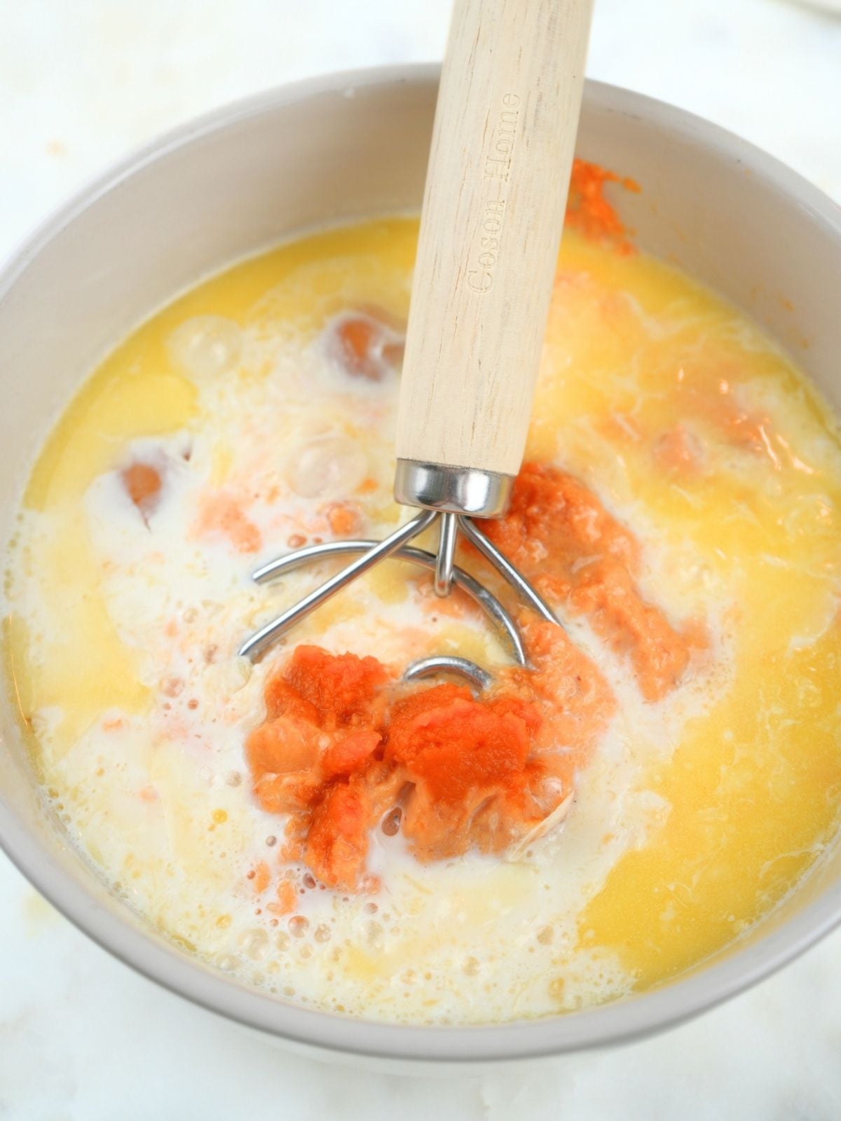 Wet ingredients in a mixing bow, shown with a Danish dough whisk.