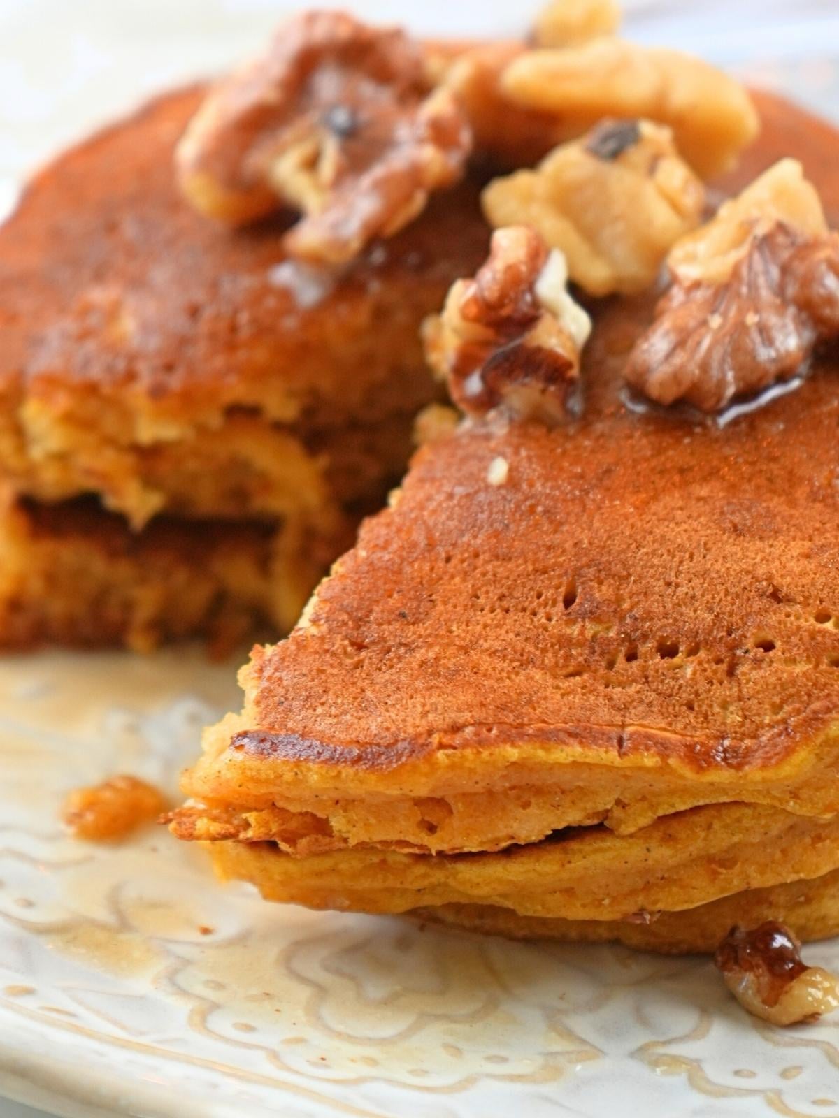A stack of pumpkin spice pancakes with a wedge cut out.