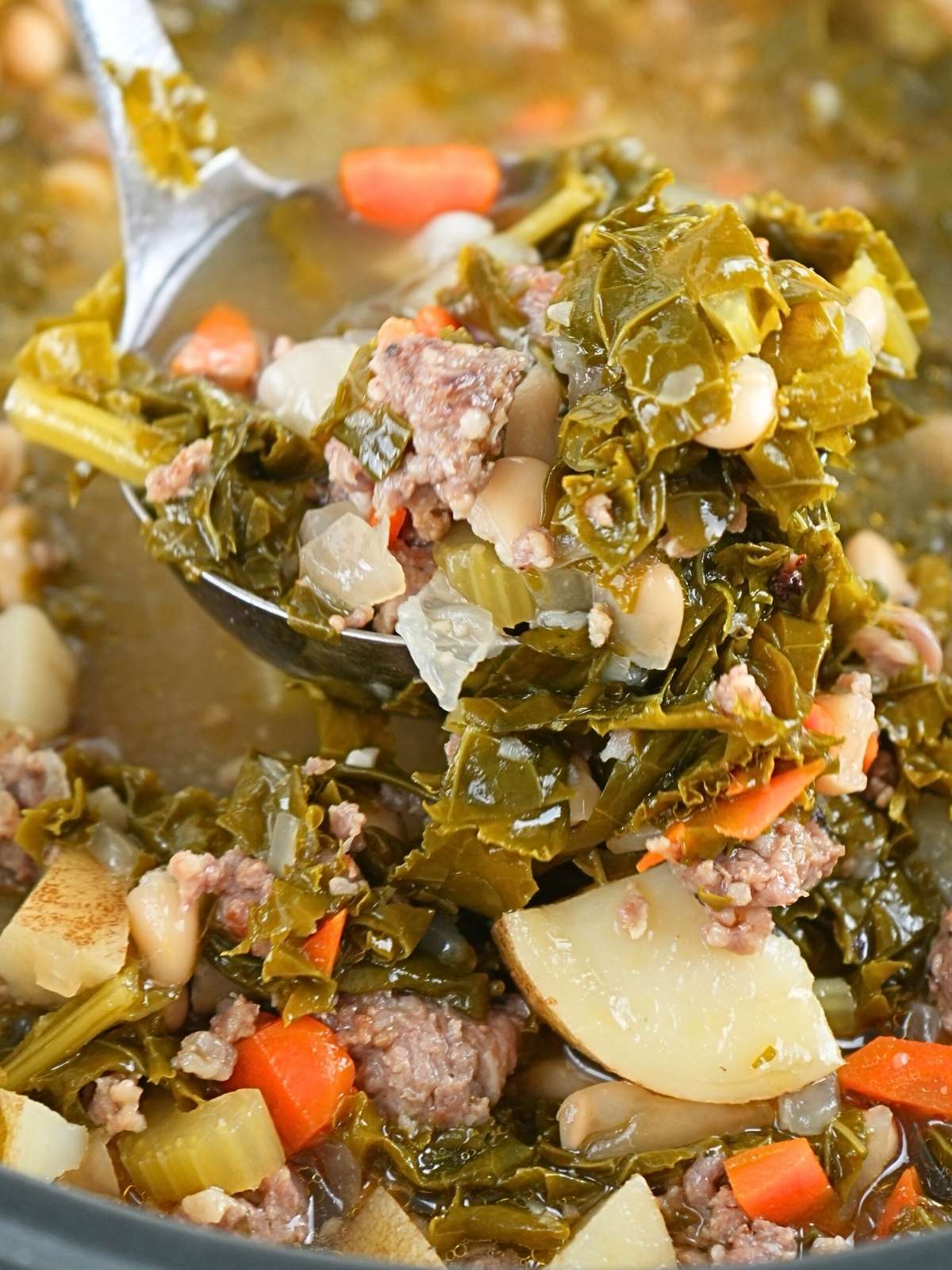 A ladle filled with sausage, kale, and white bean soup.
