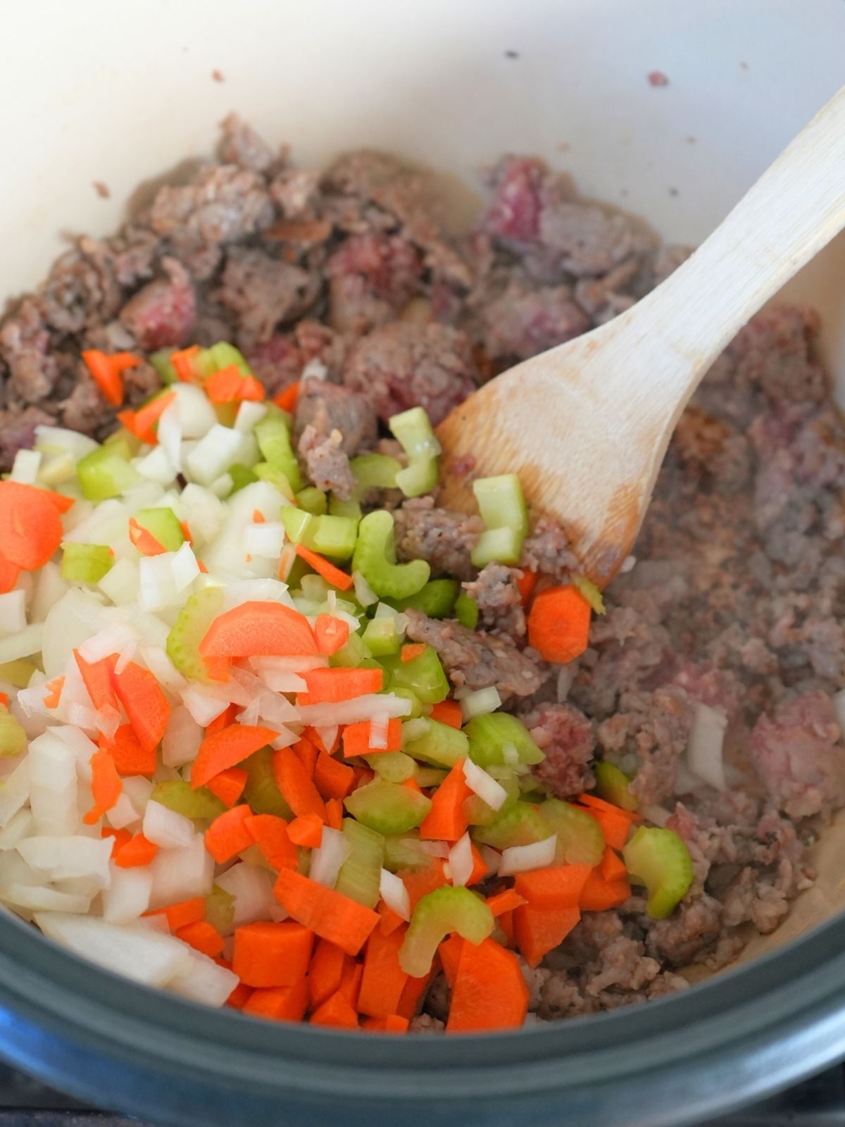 Browned sausage with chopped onions, carrots, and celery on top.