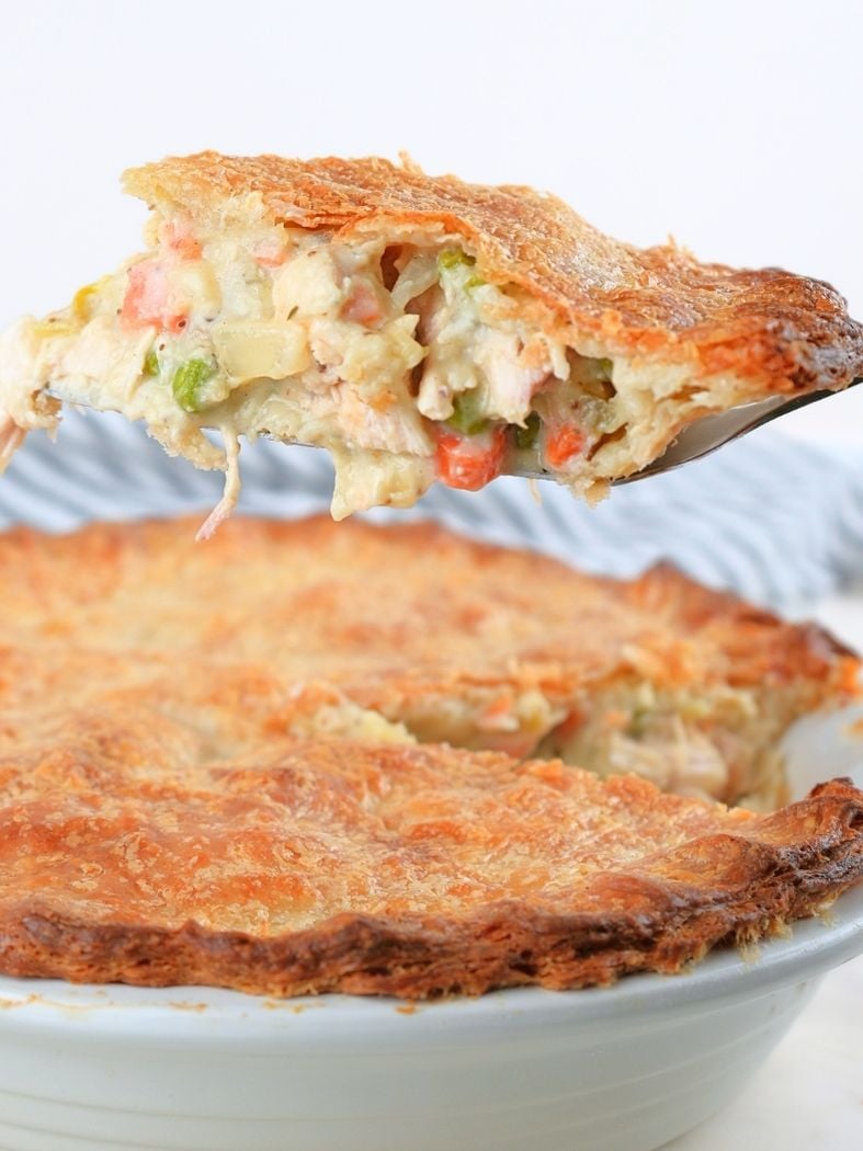 A slice of sourdough pot pie being lifted from a white pie dish