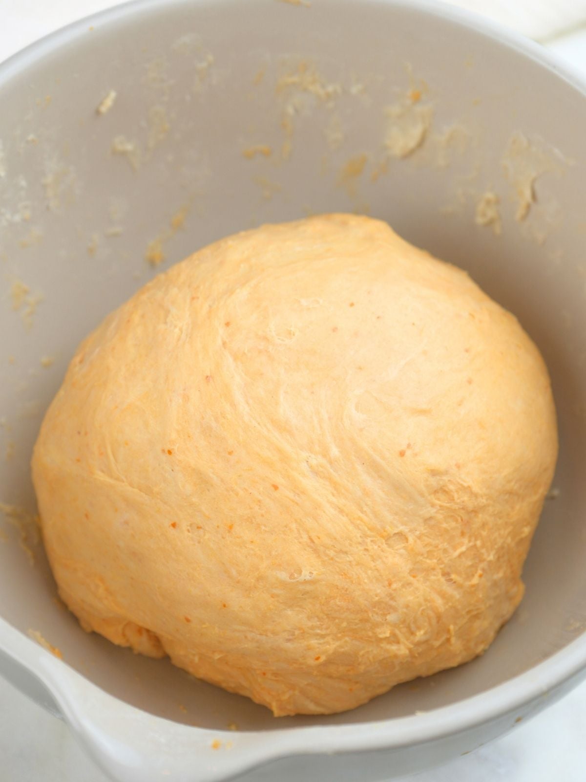 A ball of pumpkin focaccia dough in a mixing bowl.
