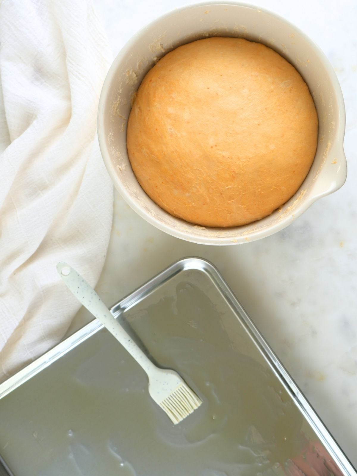 Dough in a bowl and an oiled baking sheet.