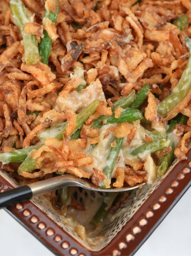 Homemade green bean casserole topped with fried onions with a spoon in it