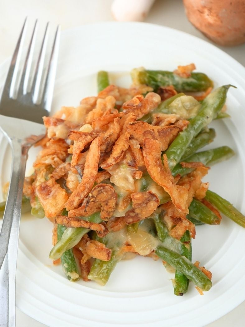 A serving of caramelized onion green bean casserole on a plate with a fork