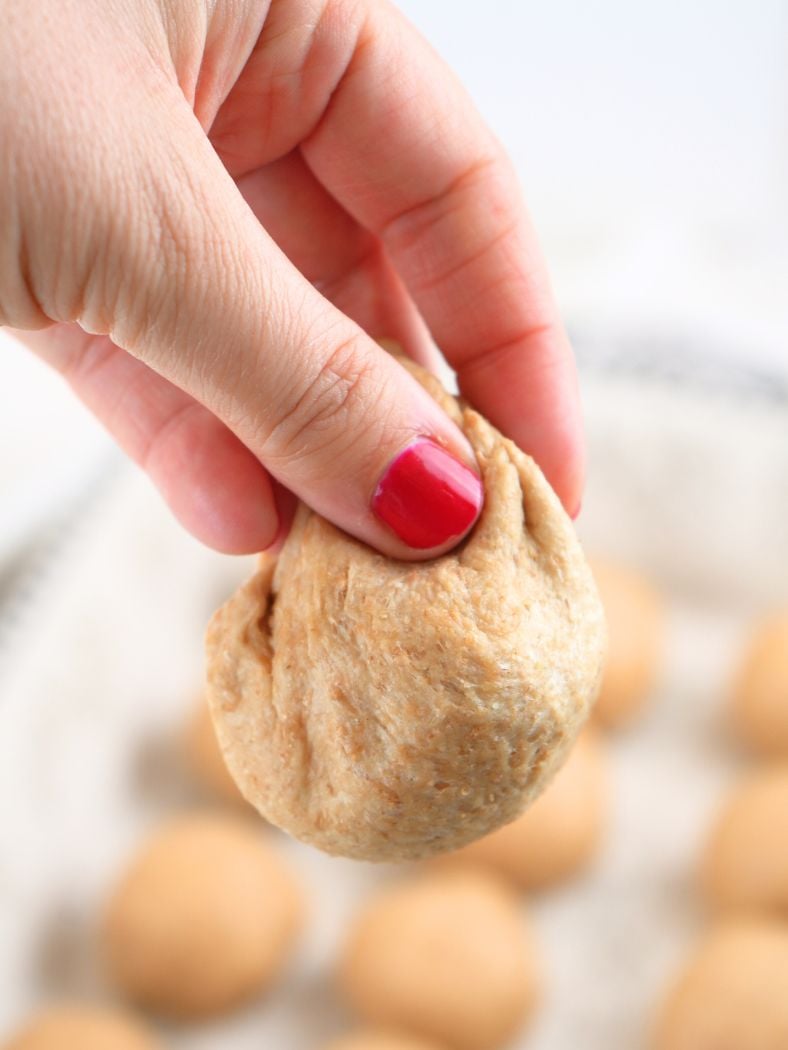 A hand holding dough, showing how to shape it