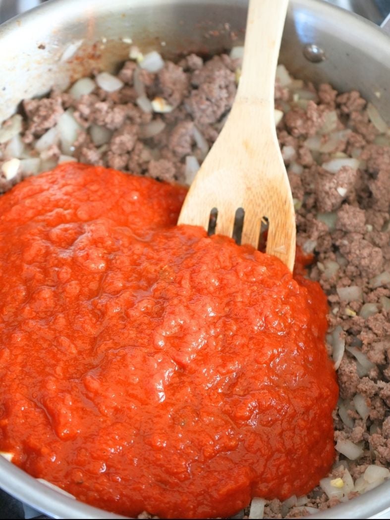 Marina sauce poured over beef mixture in a skillet