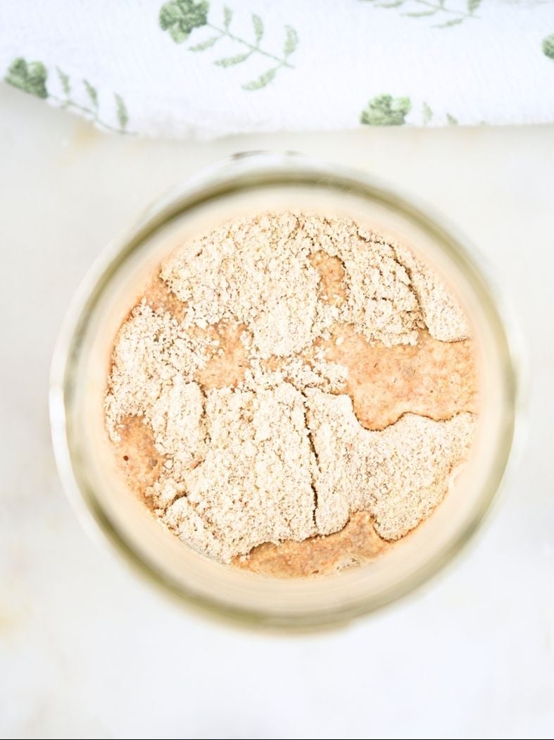 An overhead view of flour and water in a jar