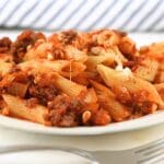 A small plate of reheated baked ziti freezer meal with a fork in the foreground