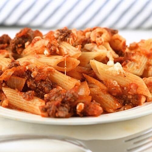 A small plate of reheated baked ziti freezer meal with a fork in the foreground