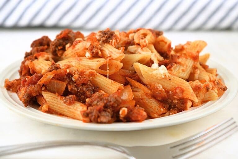 A small plate of reheated baked ziti freezer meal with a fork in the foreground