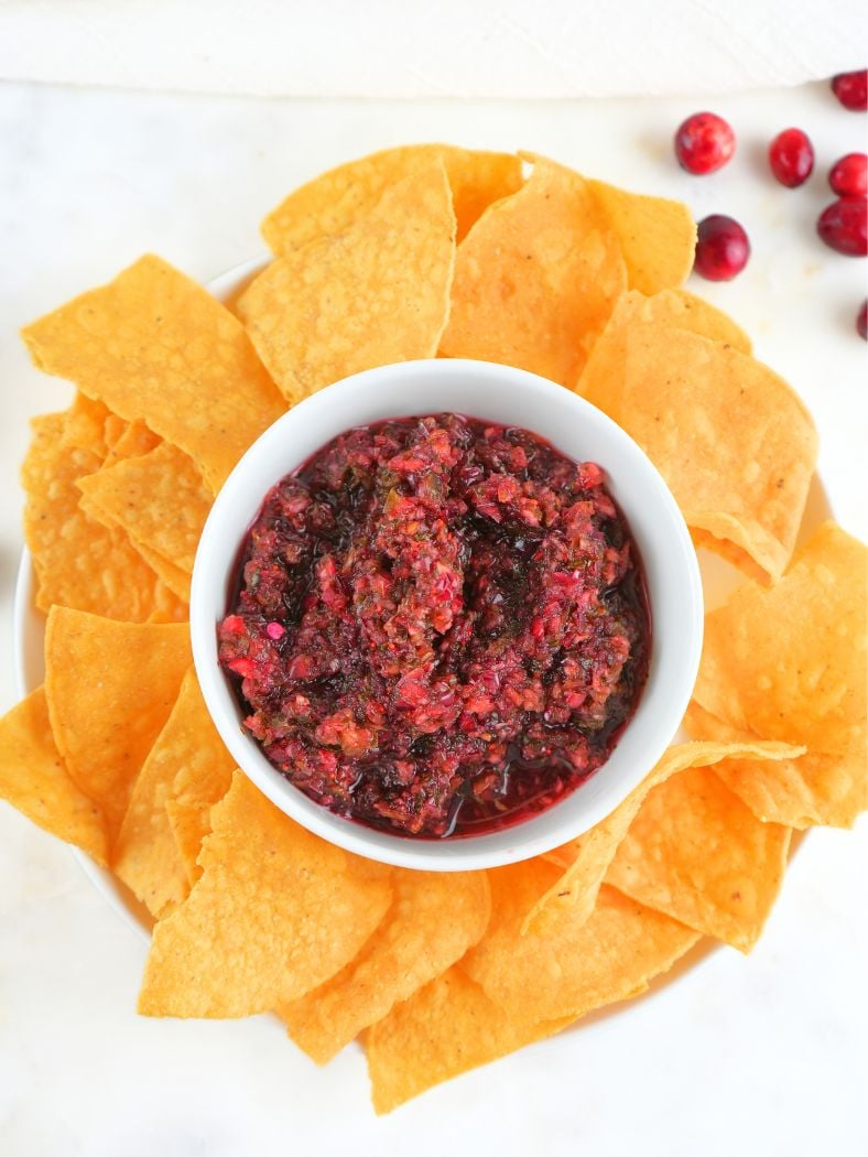 An overhead view of a platter with tortilla chips and cranberry salsa