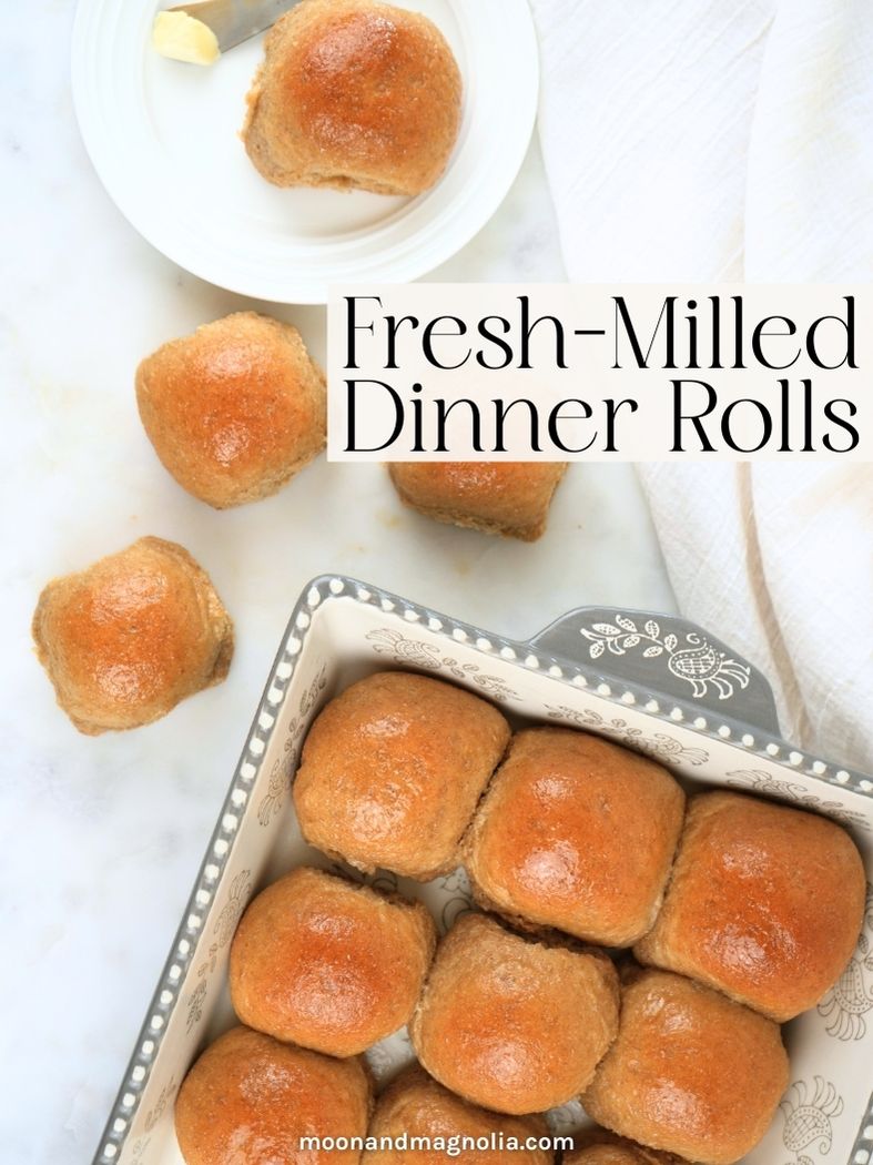 Rolls in a baking dish and scattered on a counter. Text overlay says, "Fresh-Milled Dinner Rolls"