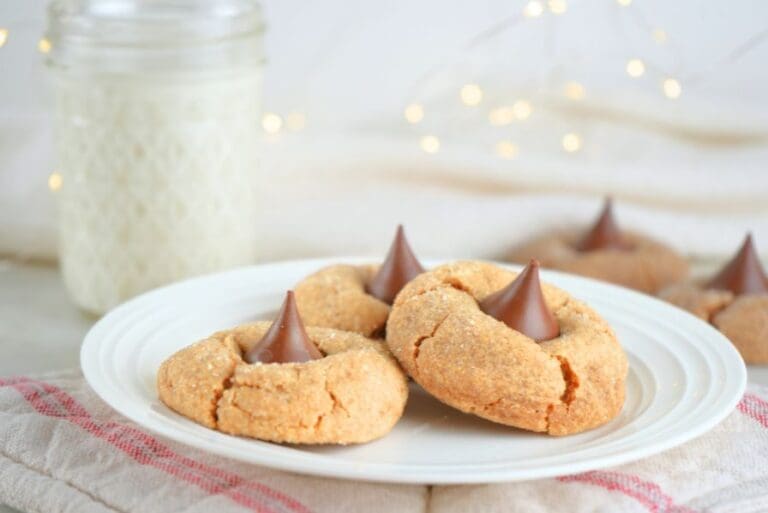A plate of three sourdough peanut butter blossoms with twinkle lights and a jar of milk in the background