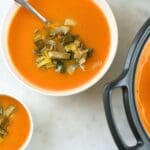 Small bowls and a Dutch oven filled with butternut squash soup with leeks