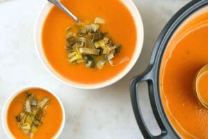 Small bowls and a Dutch oven filled with butternut squash soup with leeks